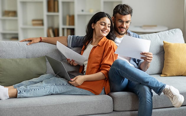 Couple sitting on couch looking at paperwork