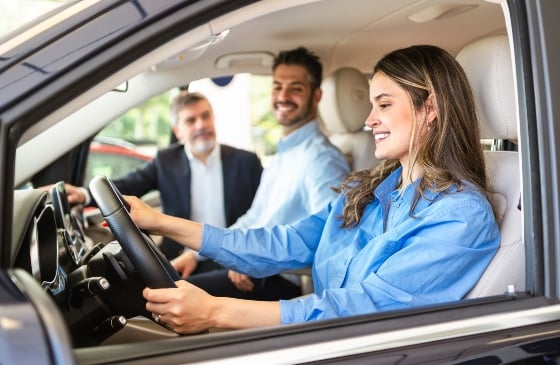 Woman and man test driving a car with sales rep outside the car.