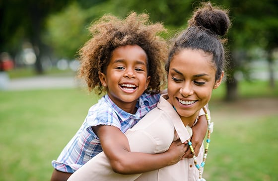 Woman holding her child smiling in a park.