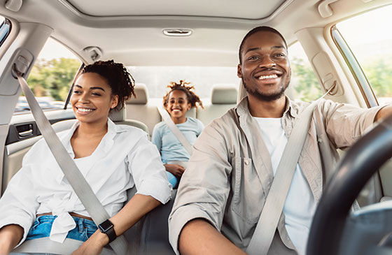 Family driving inside of a car and smiling.