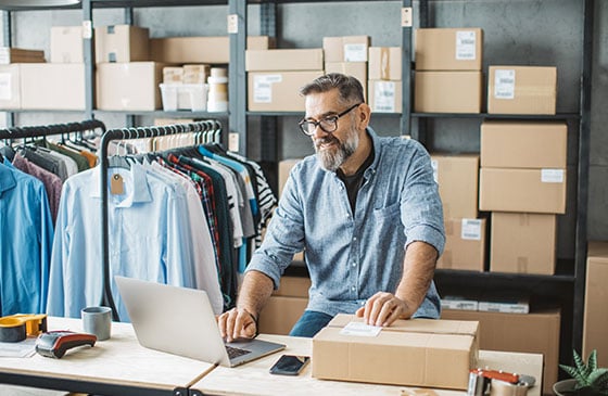 Man looking at laptop in a warehouse.