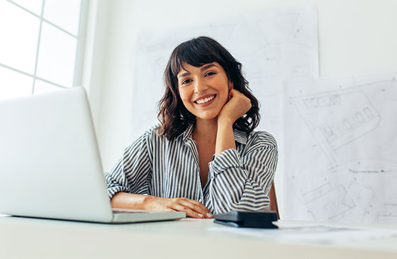 Woman sitting in front of a computer smiling.