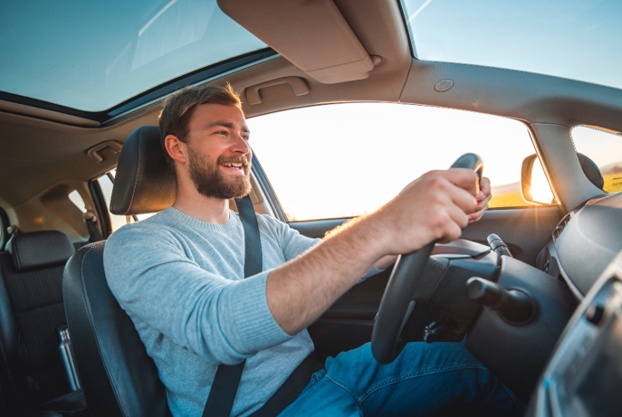 Smiling man driving inside his car.