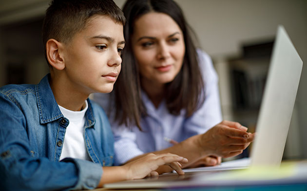 Mother and son look at laptop.