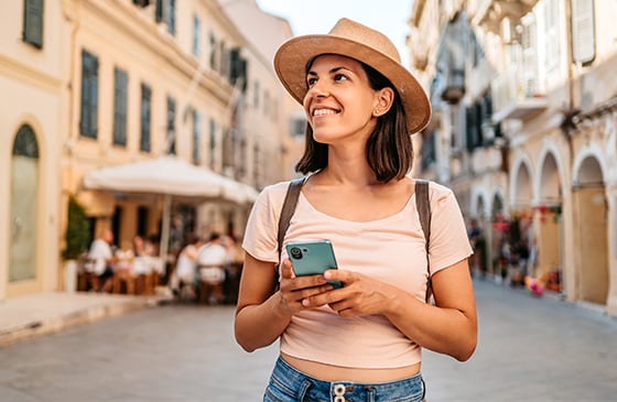 Woman setting travel alerts on her phone while walking down the street. 