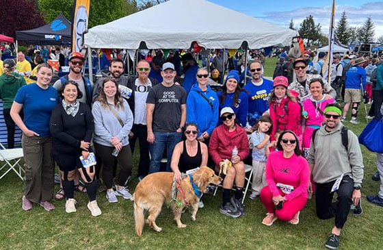 Men and women and a dog sitting outside at the SELCO tent at pool, pedal, paddle. 