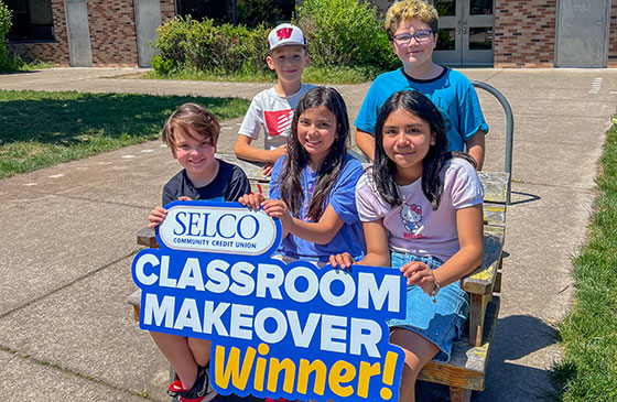 Classroom makeover winners standing in front of a school.