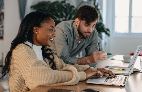 Couple at a table working together on a laptop.