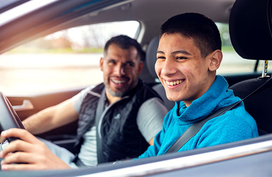 Father and son sit together in presumably the son's first car.