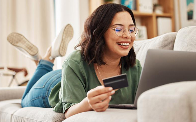 Young woman lying on couch with credit card