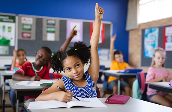 Girl raising her hand in a classroom that has has a makeover using a SELCO classroom makeover grant. 