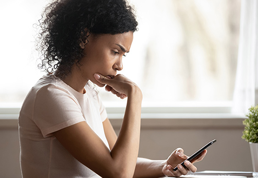 Woman sitting at a table looking at her phone. 