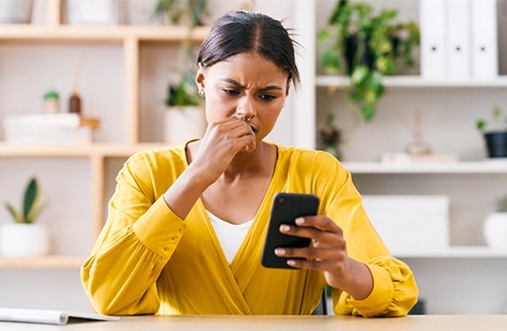 Woman sitting on her phone concerned she might have gotten a text scam.