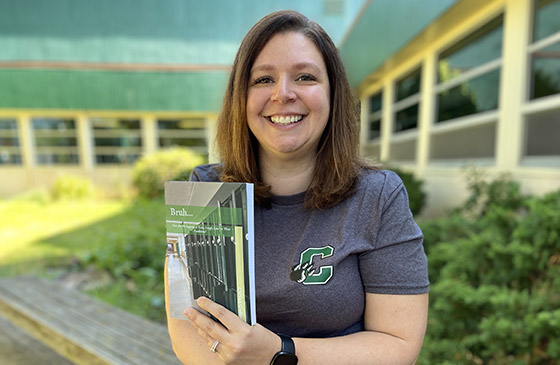 Teacher Judy Tacchini holding book outside school