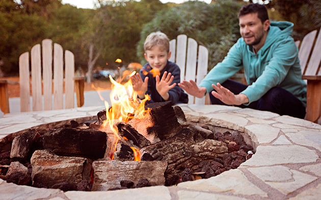 Father and son sitting near fire pit