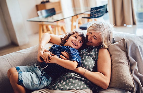 Older woman on the couch with a young child on top of her.