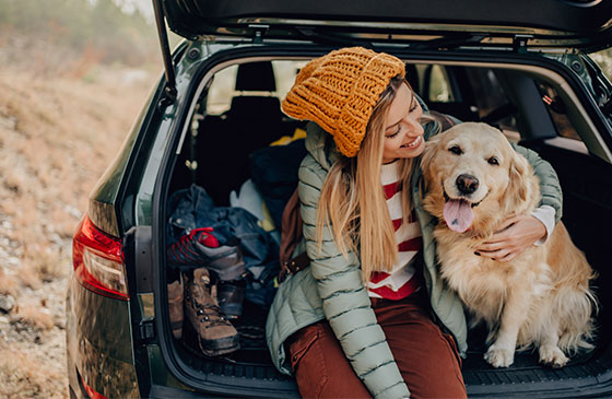 Girl sitting in the back of a car with a dog.