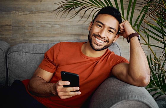 Guy sitting on a couch with his phone. 