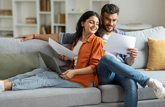 Couple sitting on couch looking at credit score report