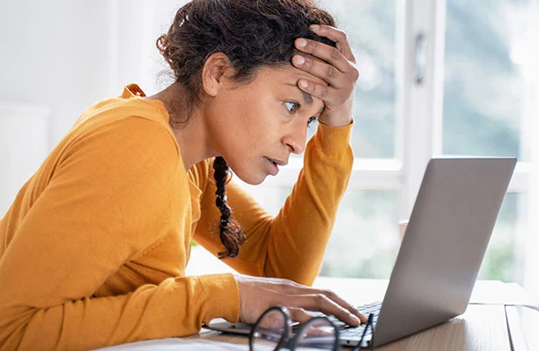 Woman sitting in front of her computer looking worried. 