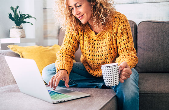 Woman using computer to calculate new mortgage payment while drinking coffee