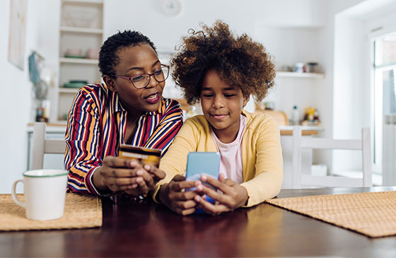 Mother and teenage daughter study a credit card together.