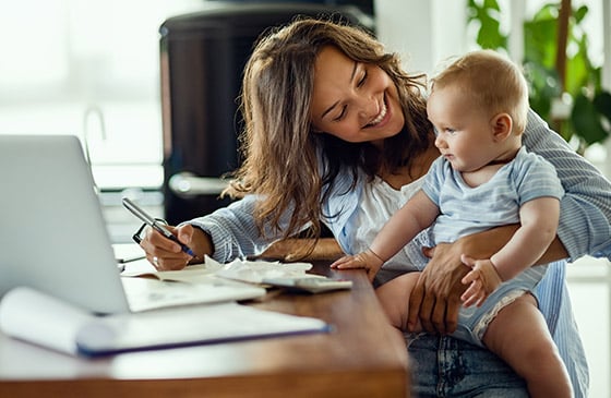 Woman sitting with her baby in front of a computer.