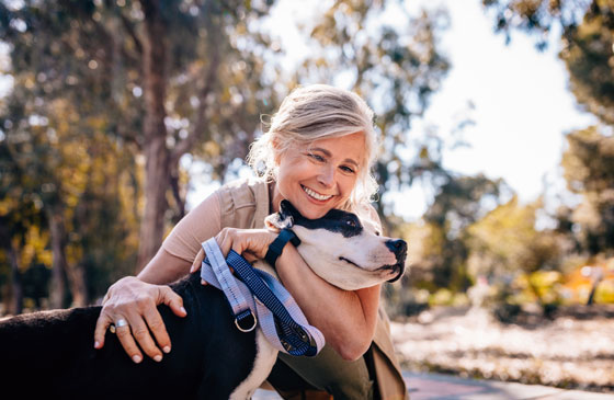 Lady happy in the park hugging dog